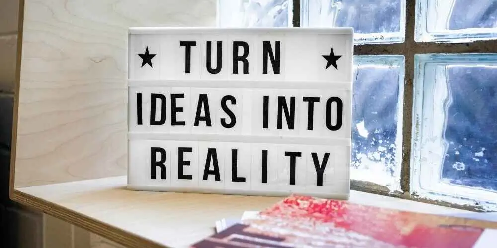 Lightbox displaying the phrase 'TURN IDEAS INTO REALITY' next to books on a windowsill, symbolizing inspiration and creativity.