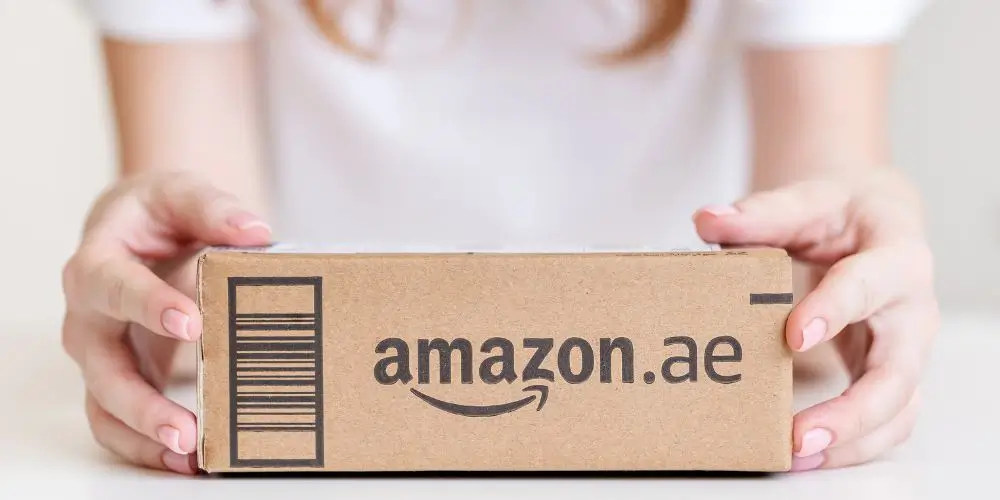 Young woman holding a cardboard box filled with delivered goods, smiling with excitement.