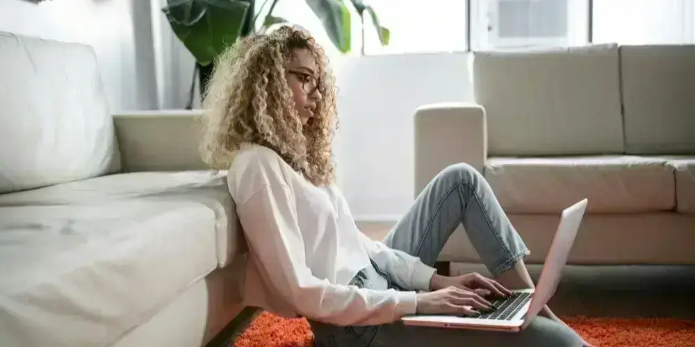 A person sitting on the floor with a laptop, looking thoughtful, symbolizing reflection and determination in overcoming challenges.