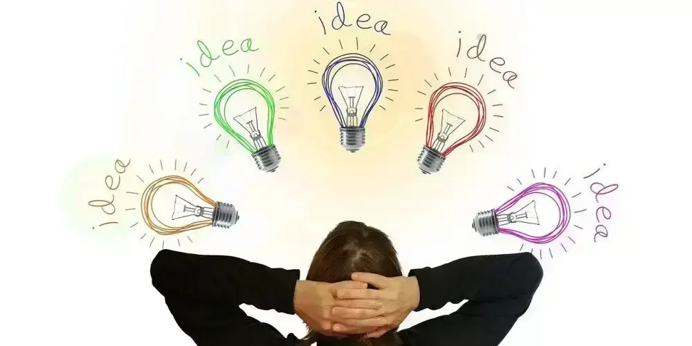 A person with hands behind their head, surrounded by colorful light bulbs labeled "idea," symbolizing brainstorming and new ideas for affiliate marketing.