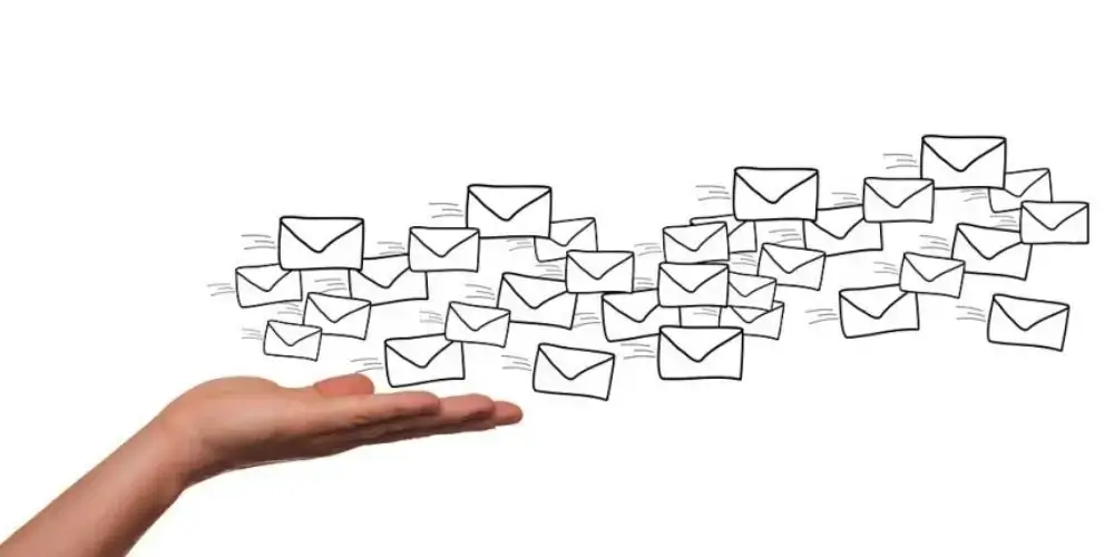 A hand holding a cluster of drawn email icons, symbolizing the flow and reach of email marketing campaigns.